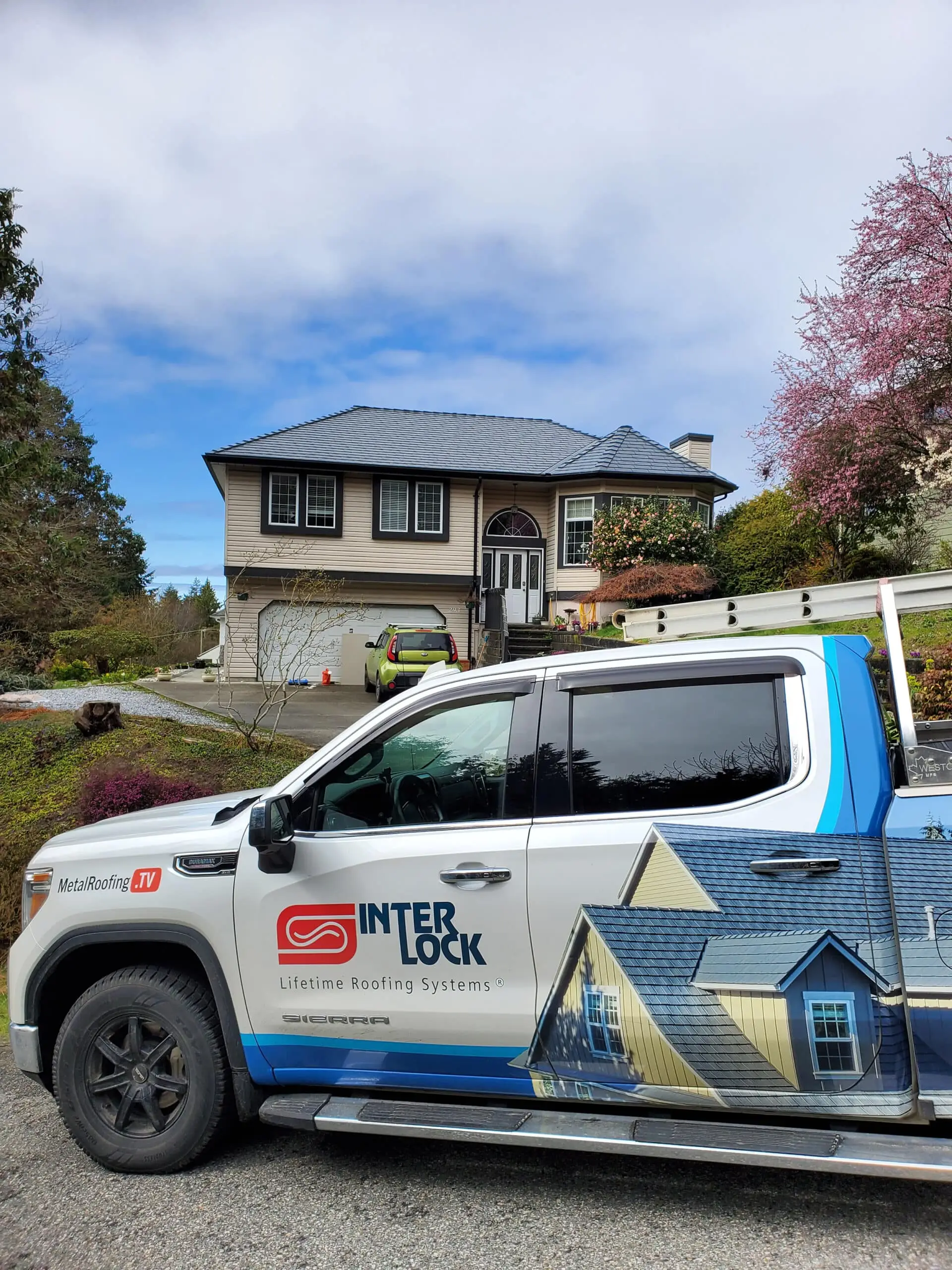 Interlock Roofing truck parked in front of residential home featuring Deep Charcoal Aluminum Interlock Slate roofing, showcasing the brand's commitment to durable metal roofing solutions.