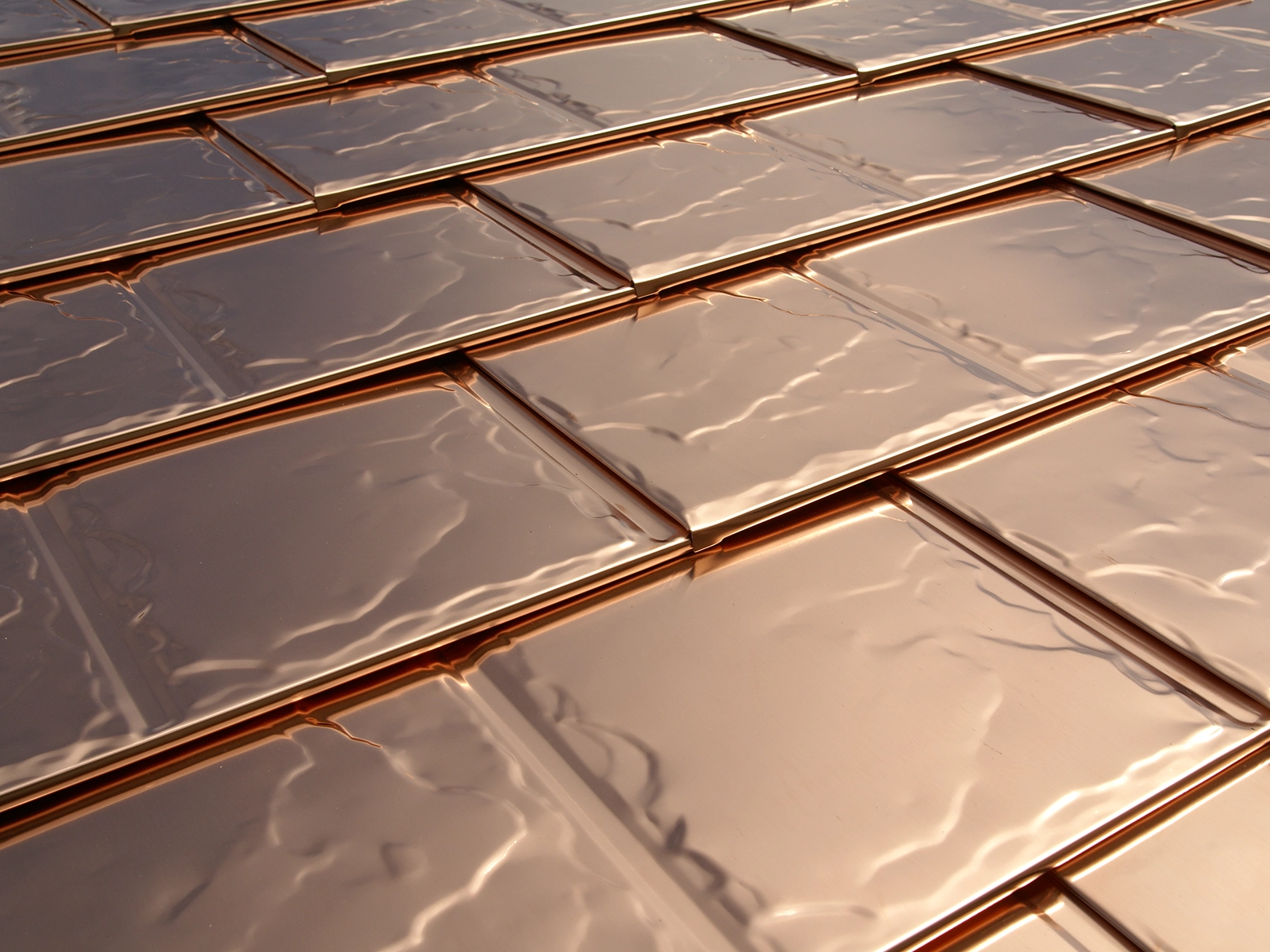 Solid copper roofing tiles showcasing a sleek, reflective surface, emphasizing durability and aesthetic appeal, relevant to long-lasting metal roofing solutions in Eufaula, WA.